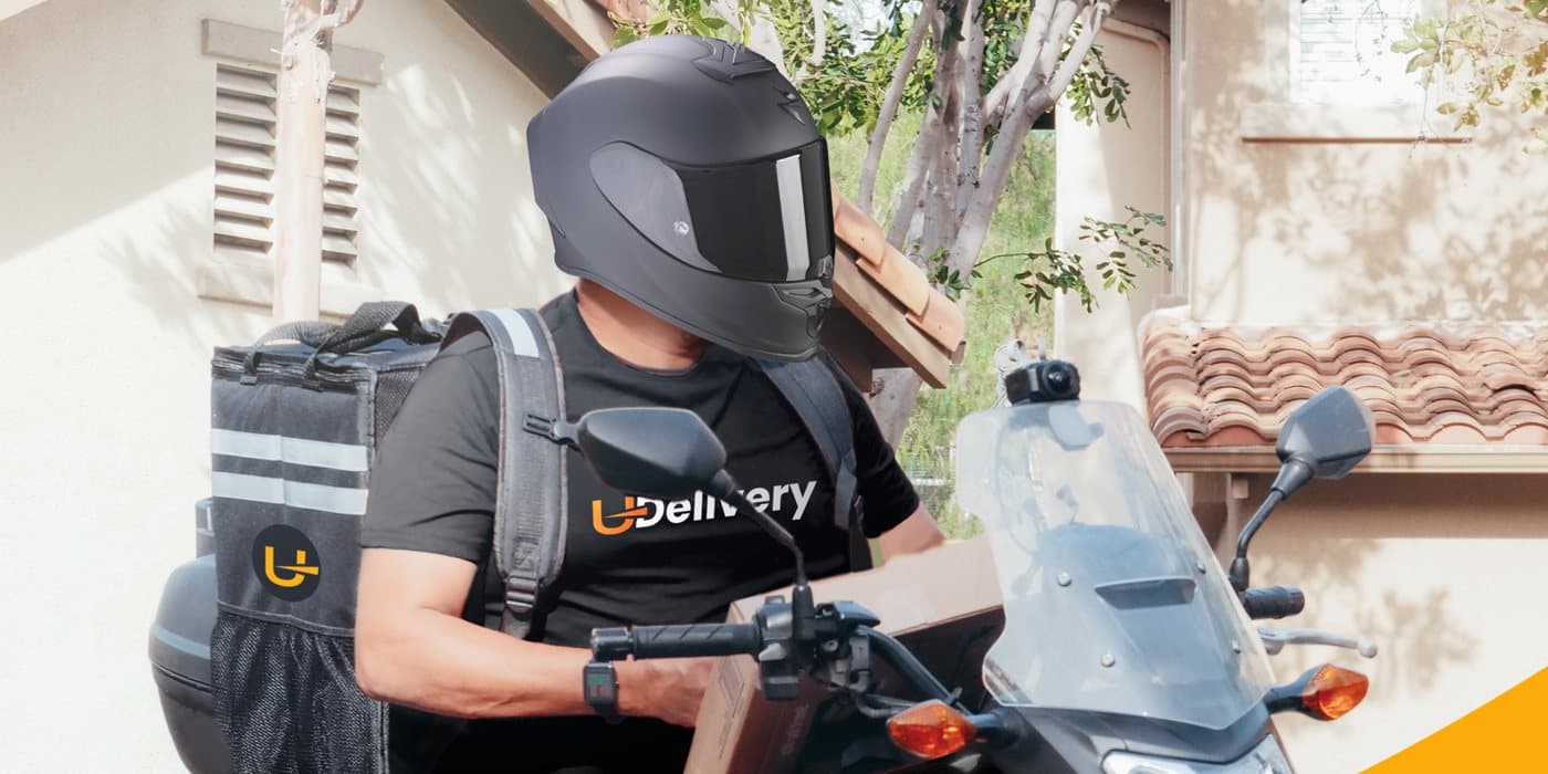 Livreur UDelivery en scooter devant une maison
